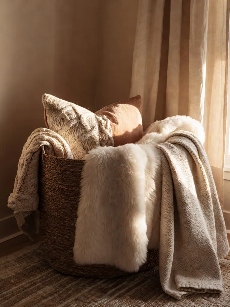 A collection of soft, textured throw blankets artfully draped over a bed and armchair, enhancing the cozy bedroom aestheti...