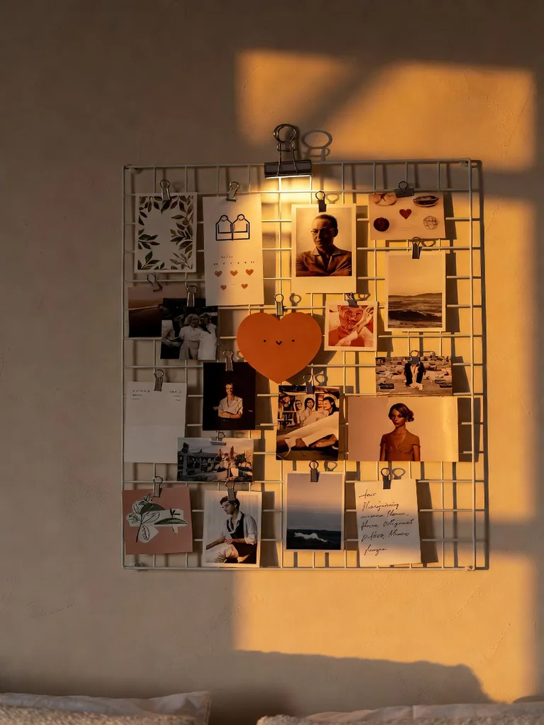 Memory board in a cozy bedroom with fairy lights, framed photos, and mementos, adding personalized decor.