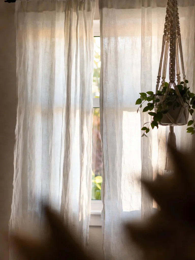 Flowing white curtains softening the hard edges of a bedroom window, creating a cozy and inviting atmosphere.