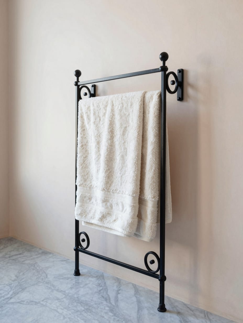 Decorative black wrought iron towel rack with scrolled ends mounted on a white wall.