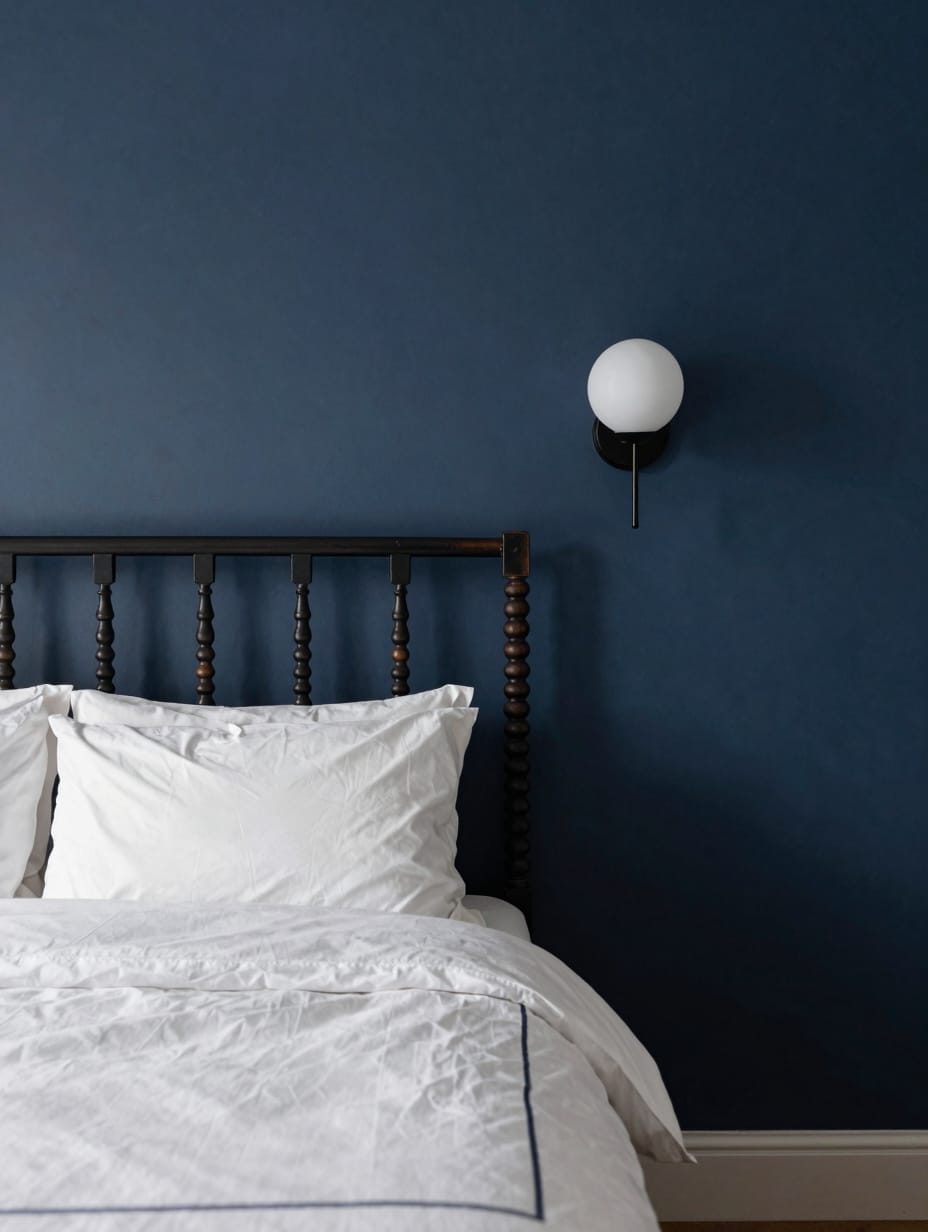 A deep midnight blue accent wall behind a mid century modern dresser.