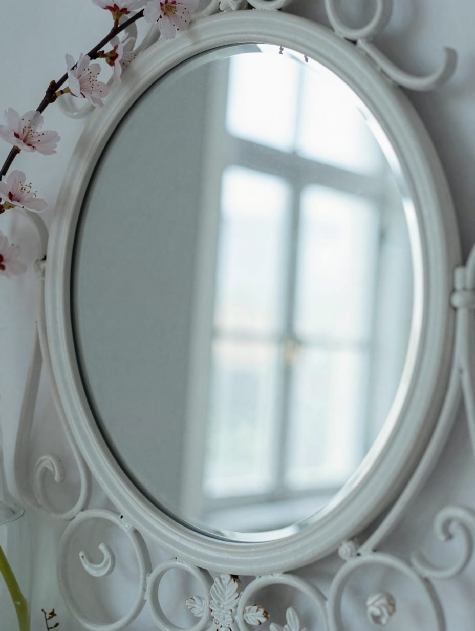 An ornate gold framed mirror hanging above a pedestal sink in a powder room.