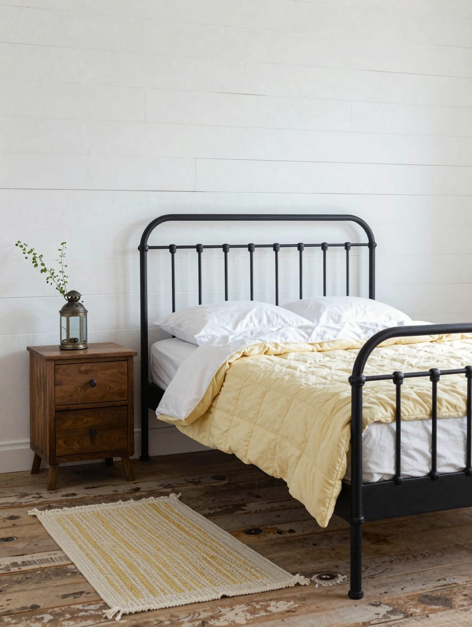 A modern farmhouse bedroom with a dark iron bed, wood accents, and a butter yellow plaid throw.